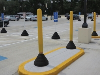 yellow plastic bollard post with black rubber base in use in parking lot